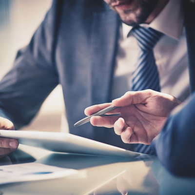Image of two young businessmen using touchpad at meeting